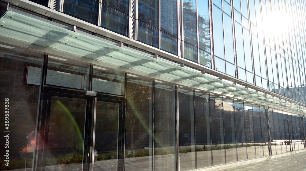 Blue curtain wall made of toned glass and steel constructions under blue sky. A fragment of a buildi