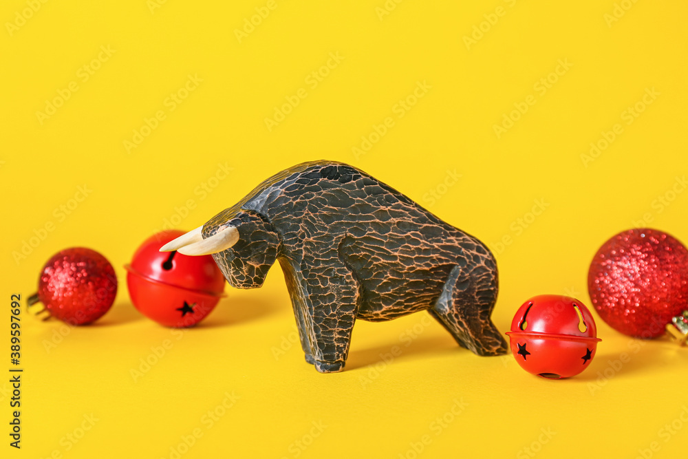 Figurine of bull and New Year decor on color background