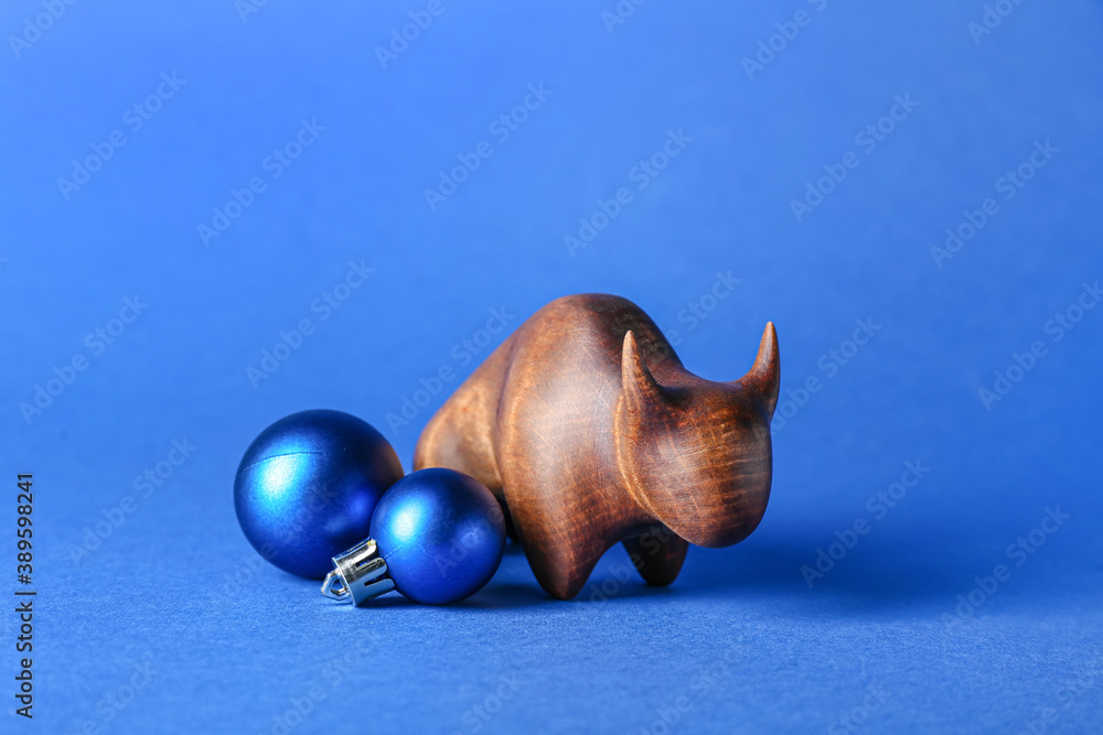 Figurine of bull and New Year decor on color background