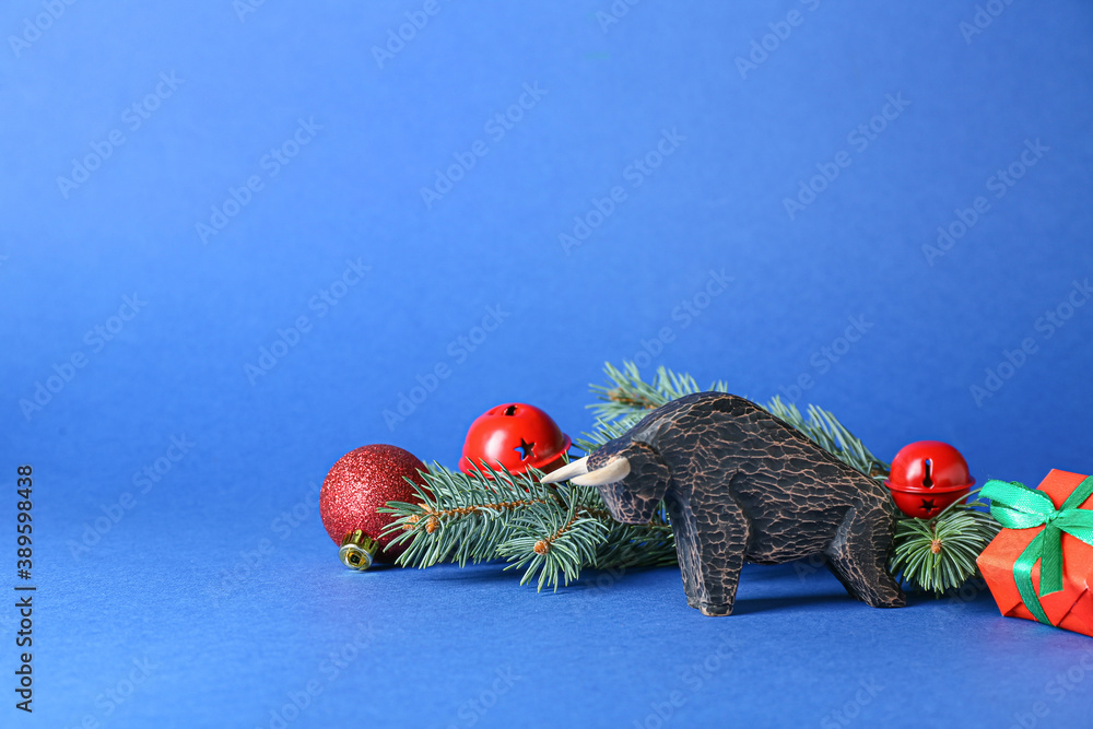 Figurine of bull and New Year decor on color background