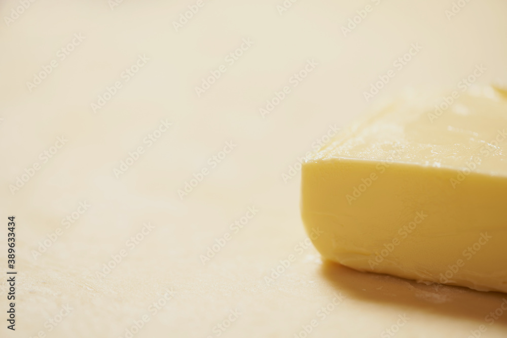 Close-up of a piece of butter is on the rolled raw dough