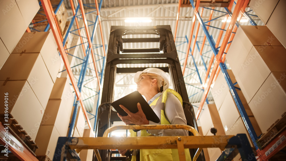 Professional Female Worker Wearing Hard Hat Lifts Herself on Aerial Work Platform to Check Stock and