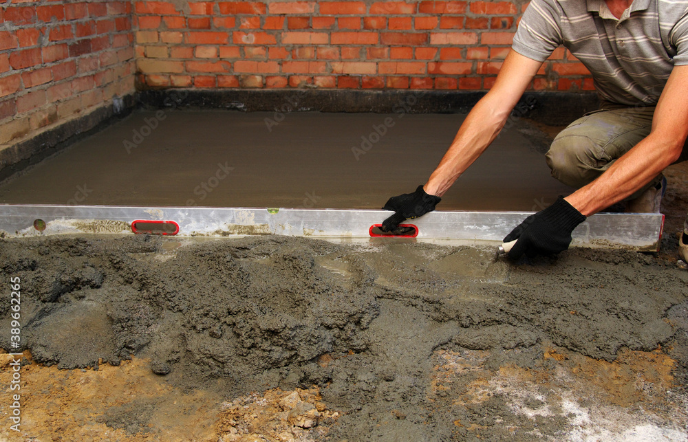 worker screeding indoor cement floor with screed