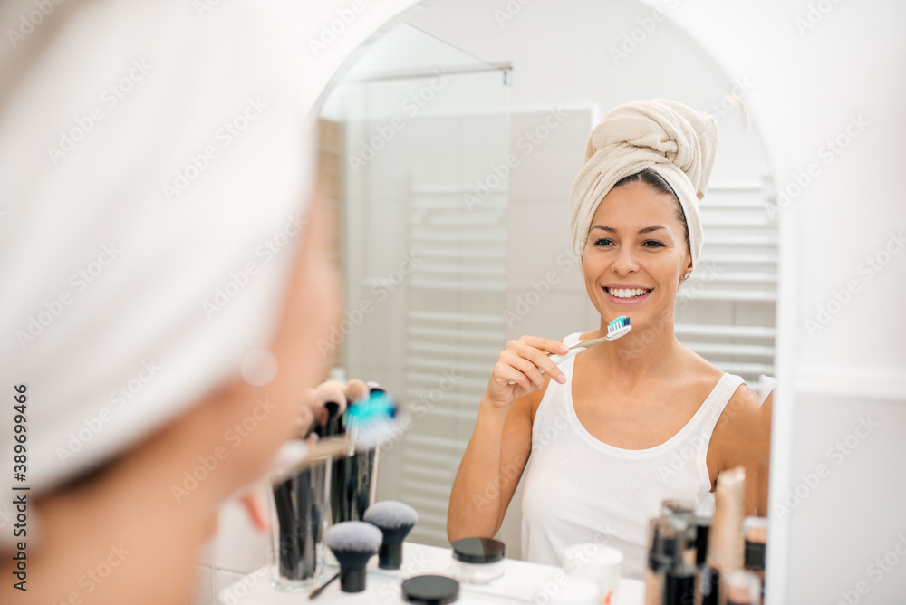 Young smiling woman brushing teeth.