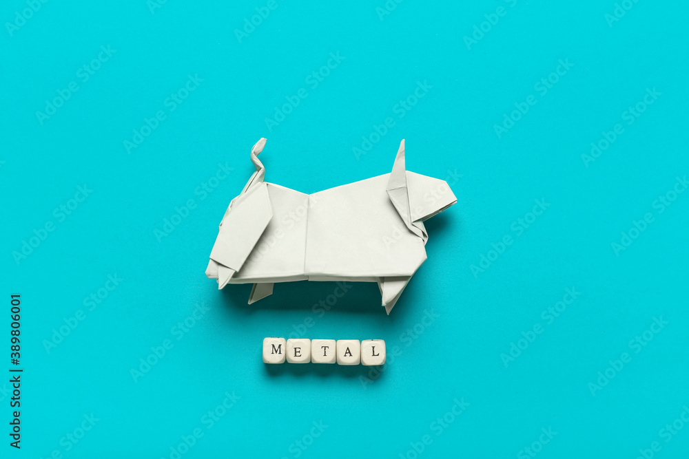 Origami bull as symbol of year 2021 and word METAL made of cubes on color background