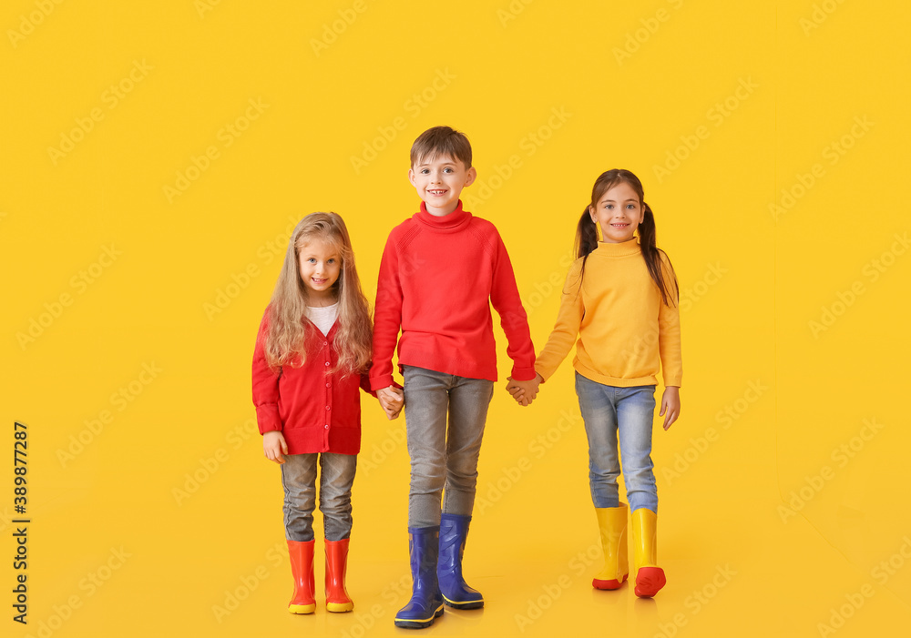 Cute little children in autumn clothes on color background