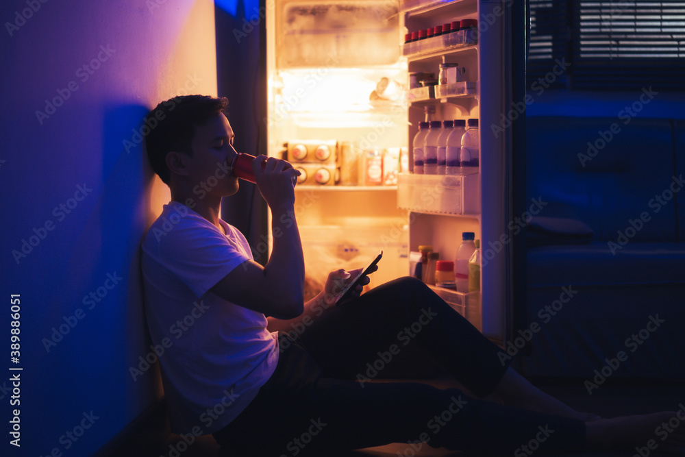 Asian men he is opening the refrigerator.Drank soft drinks during the night, he used the phone.