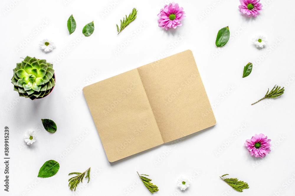 Notebook with flower petals on white table background top view mock-up