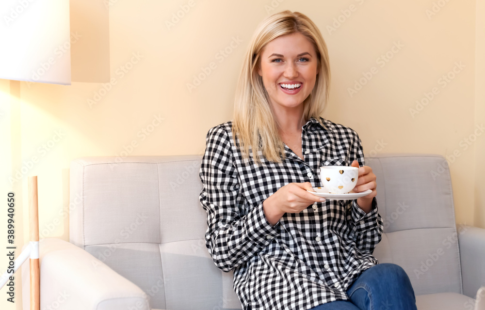 Happy young woman drinking coffee at home