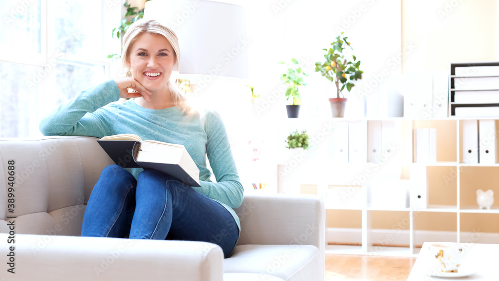 Young woman reading a big book at home