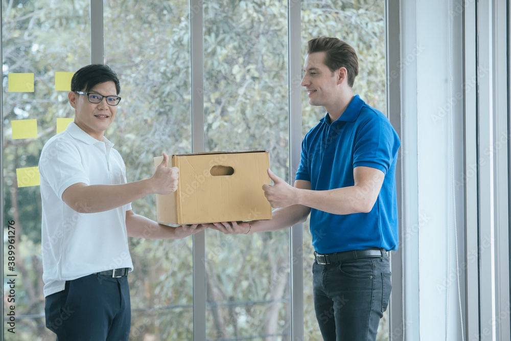 Delivery staff in blue uniform handing a parcel box over to a customer,Shopping Commercial Online In