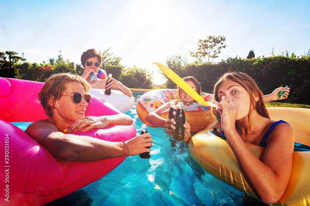 Many teenage kids blow noisemaker make party in the swimming pool with friends laugh and celebrate