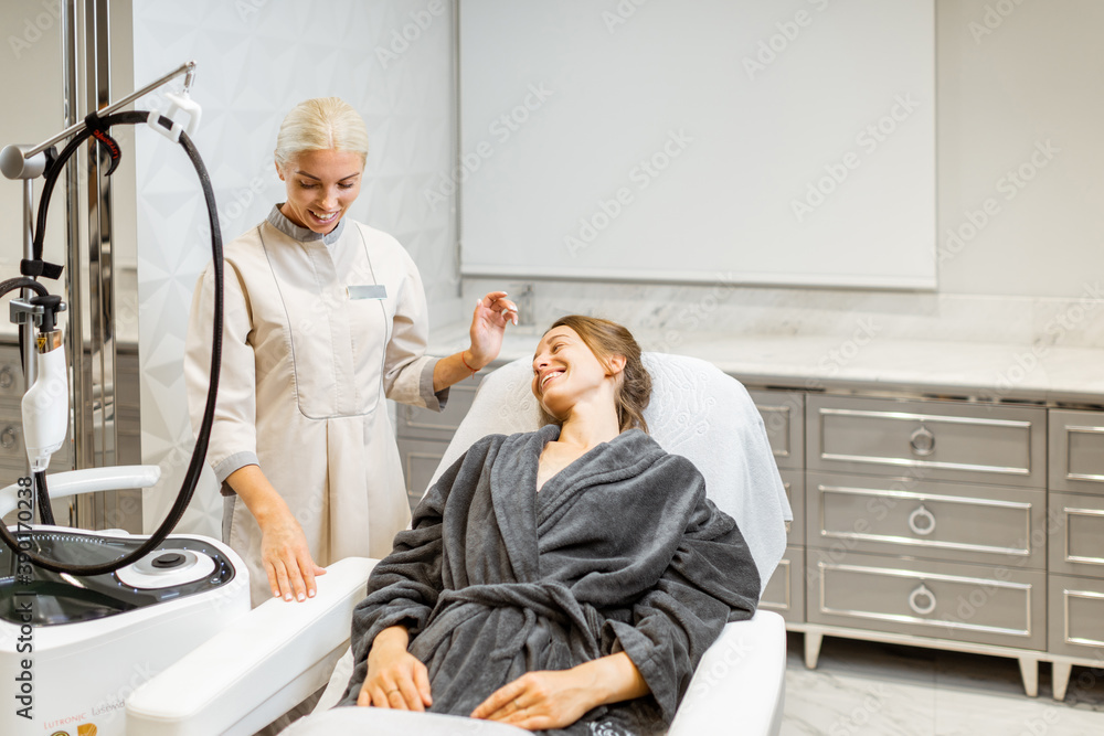 Young woman client with a doctor during a facial rejuvenation treatment at medical SPA office. Conce