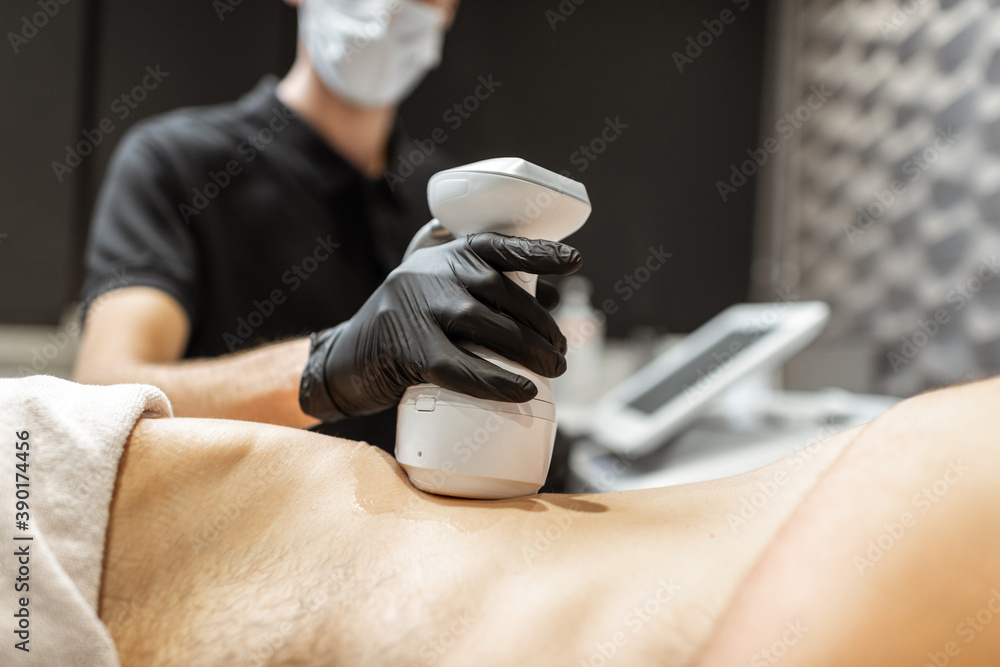 Man during an ultrasound liposuction procedure at luxury Spa salon. Doctor working on waist side are