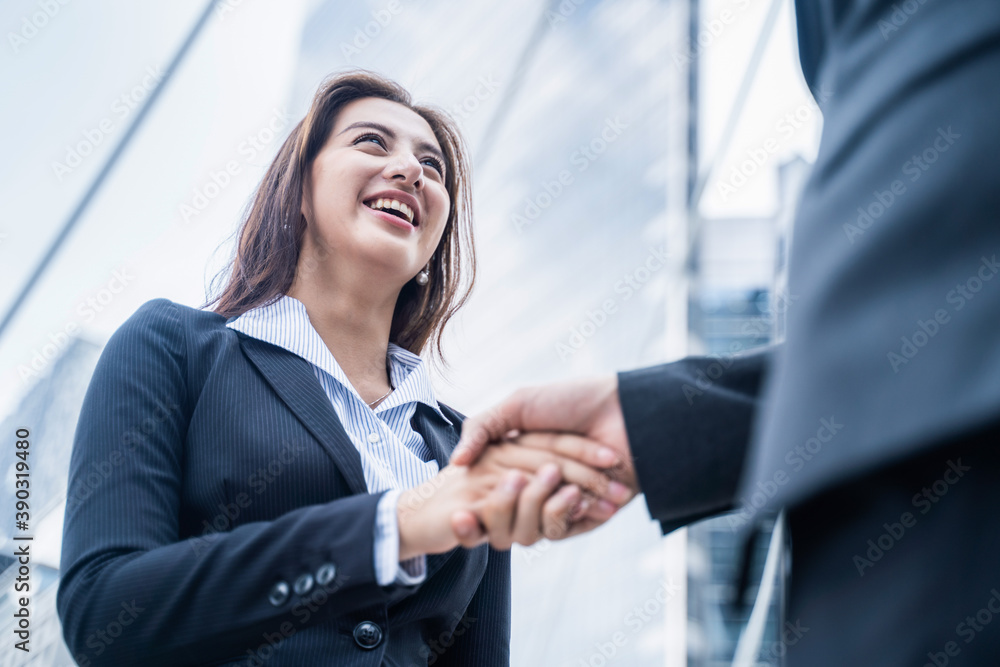 Asian businesswoman make handshake in city with building background.