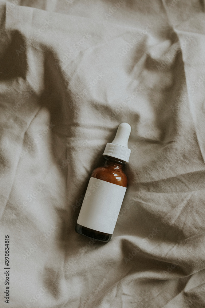 Amber dropper bottle on gray fabric background