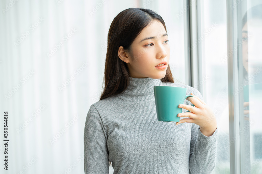 Asian woman drinking coffee by the window during break
