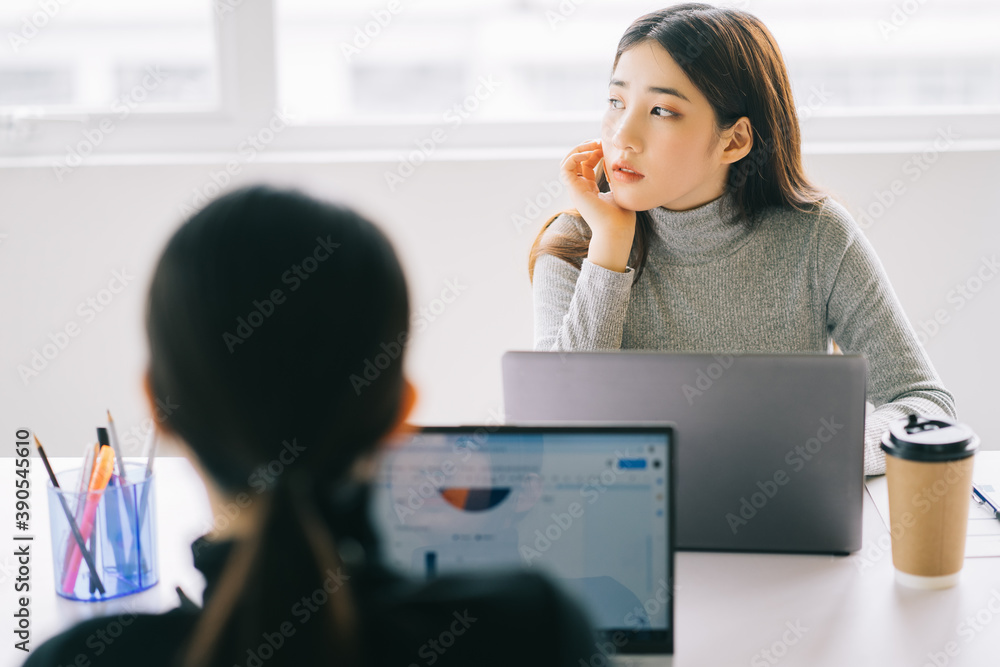 two asian business women are gathered in the office