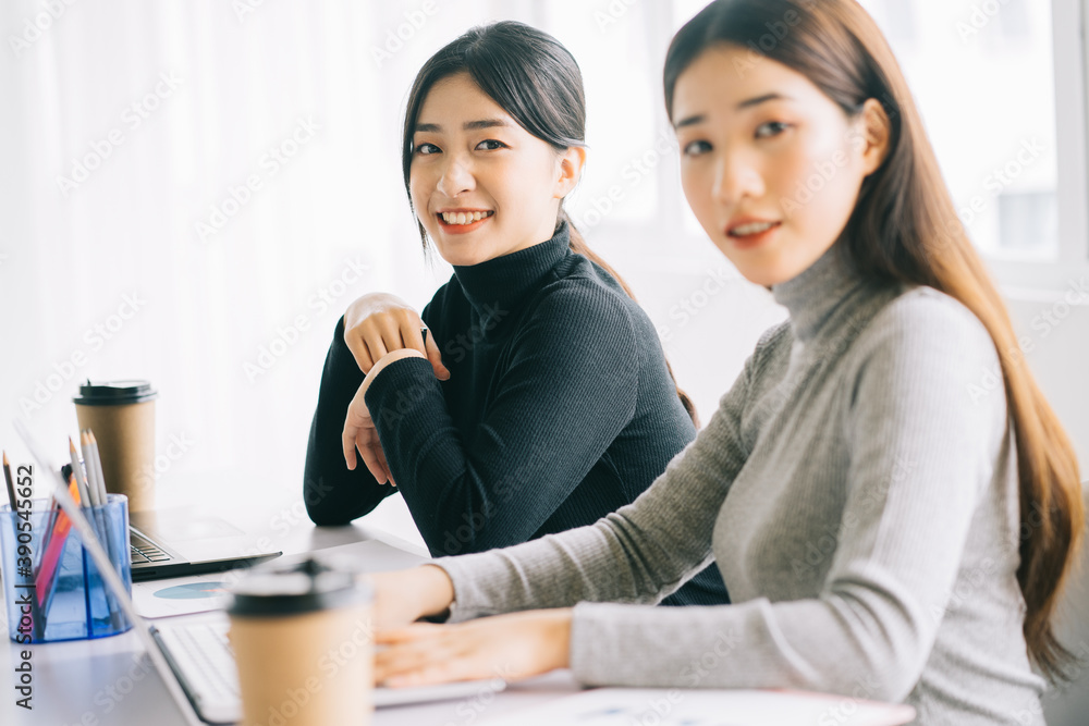 two asian business women are gathered in the office