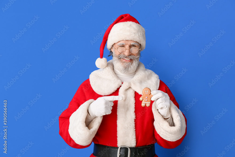 Santa Claus with tasty gingerbread cookie on color background