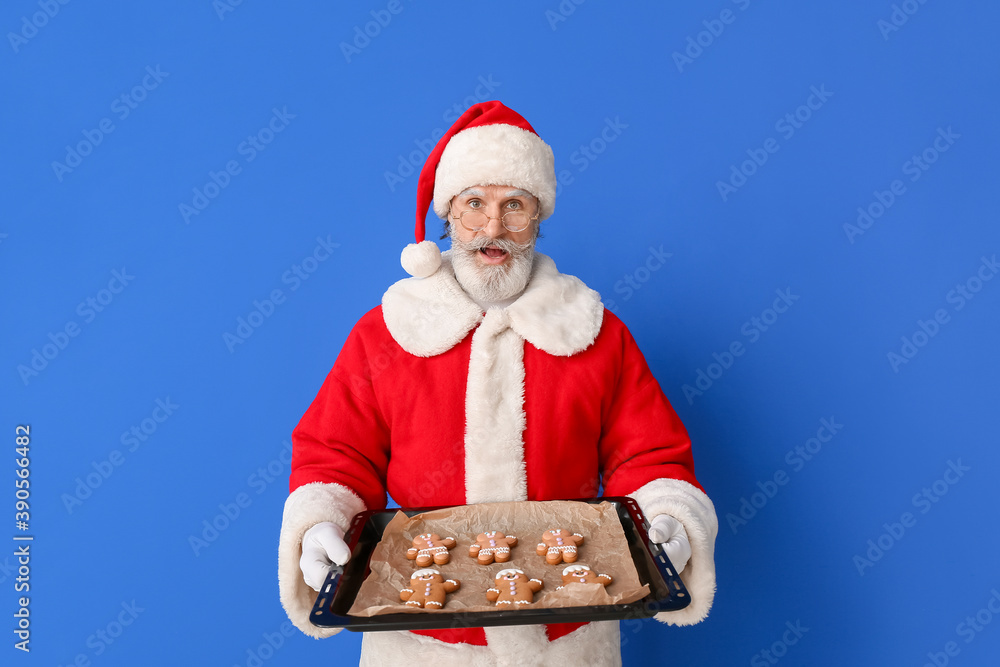 Santa Claus with tasty gingerbread cookies on color background