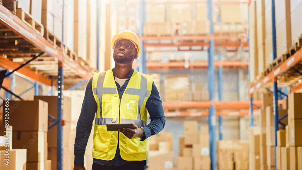 Handsome Male Worker Wearing Hard Hat Checks Products Stock and Inventory with Digital Tablet Comput