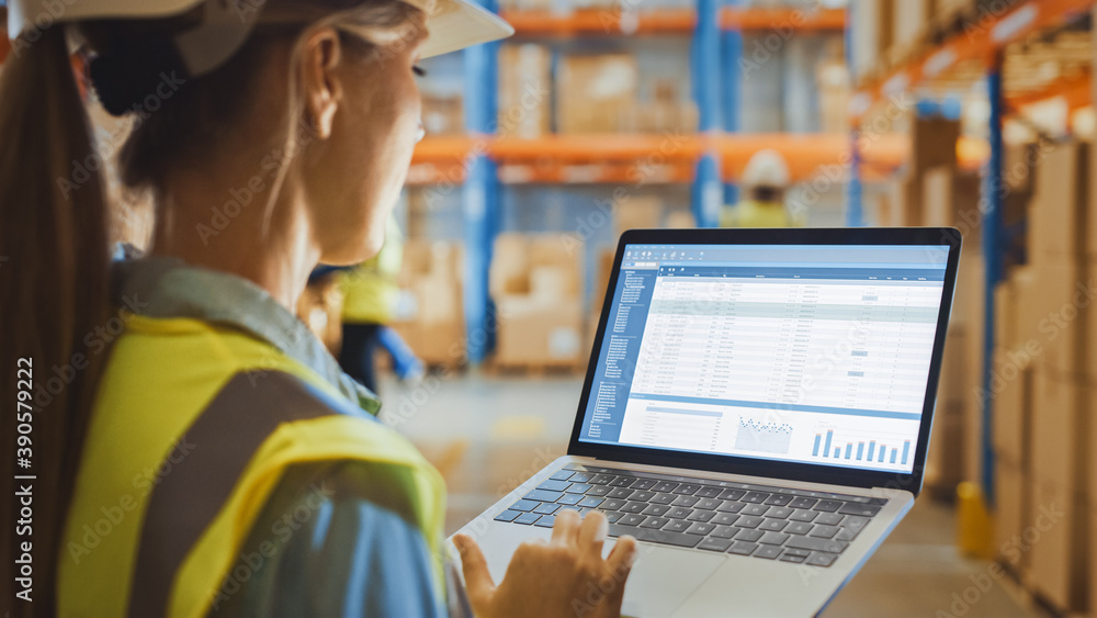 Professional Female Worker Wearing Hard Hat Holds Laptop Computer with Screen Showing Inventory Chec