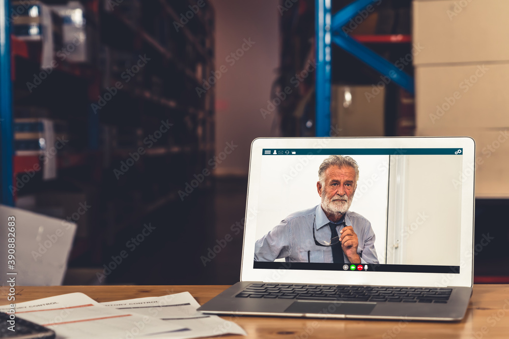 Warehouse staff talking on video call at computer screen in storage warehouse . Online software tech