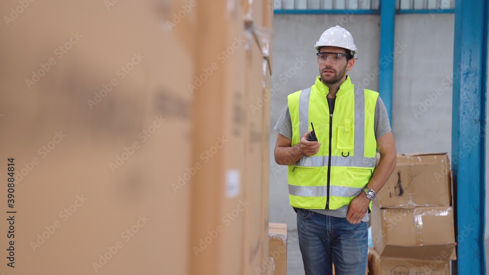 Professional cargo worker talks on portable radio to contact another worker . Factory and warehouse 