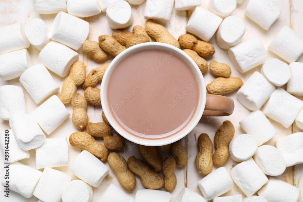 Cup of hot cacao drink with marshmallows and peanuts on table