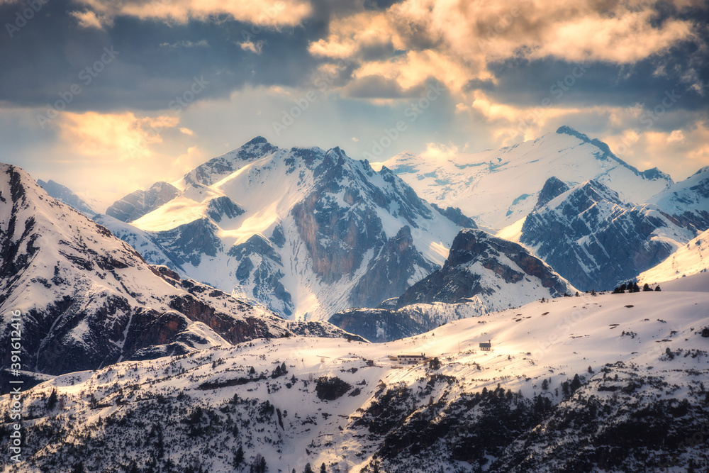 Snowy mountains is lighted by sunbeam at sunset in winter. landscape with beautiful snow covered roc