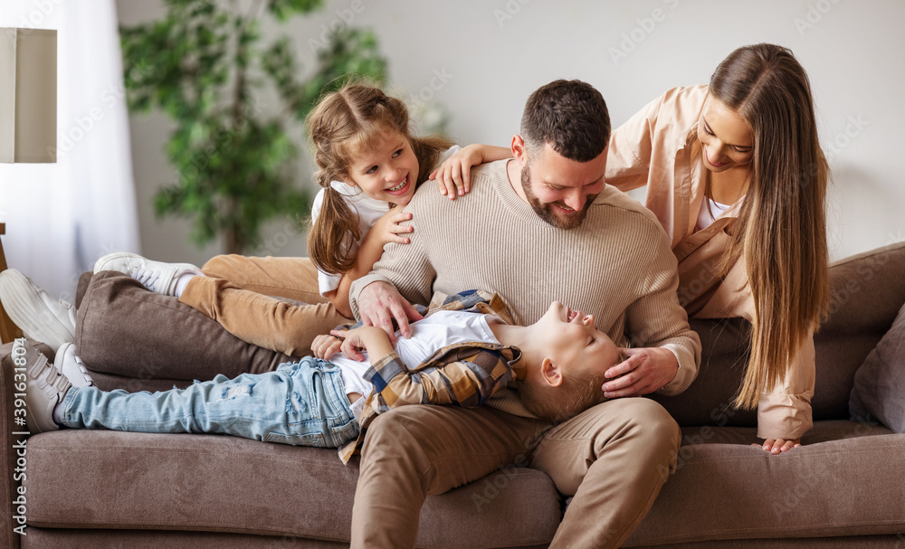 happy family mother father and kids having fun at home on couch