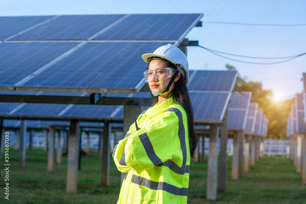 Engineer women wearing safety vest and safety helmet standing in front of solar panels,renewable and