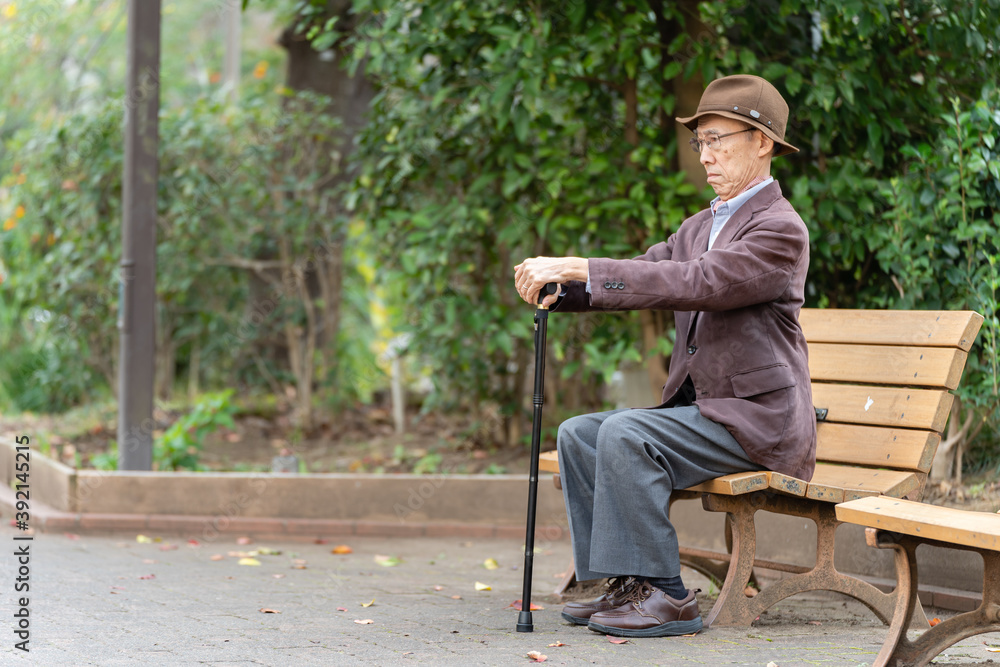 公園でベンチに座るシニア男性