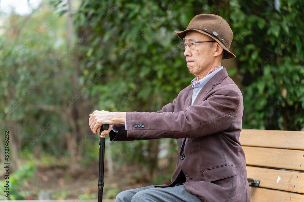 公園でベンチに座るシニア男性