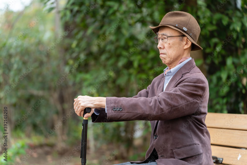 公園でベンチに座るシニア男性