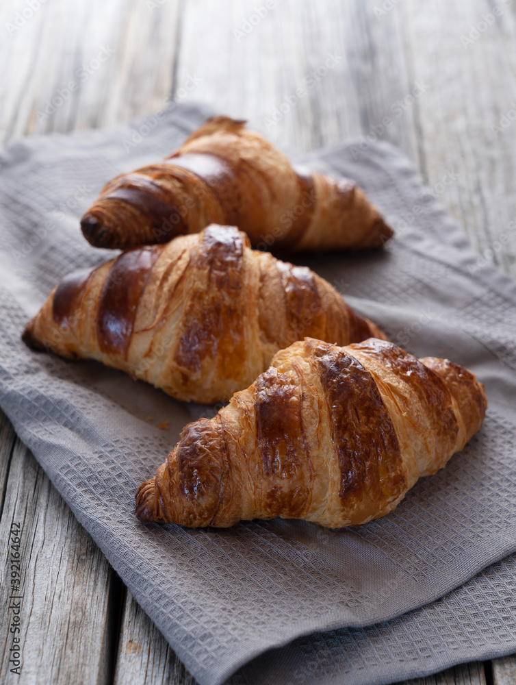 Croissant on a cloth placed against an old wooden background