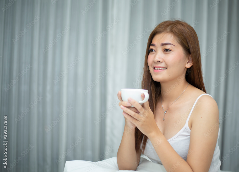 一名亚洲女子在私人卧室醒来后，喝着早上的咖啡。