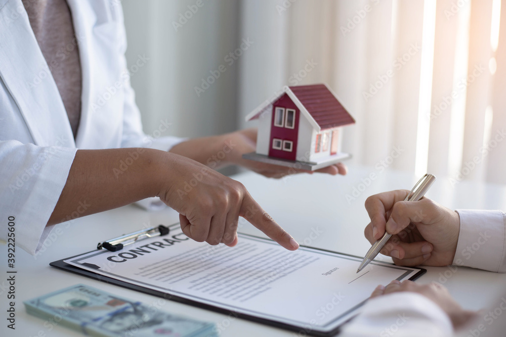 Agreeing to buy a house, a mans hand is about to sign an agreement or a contract for buying a home 