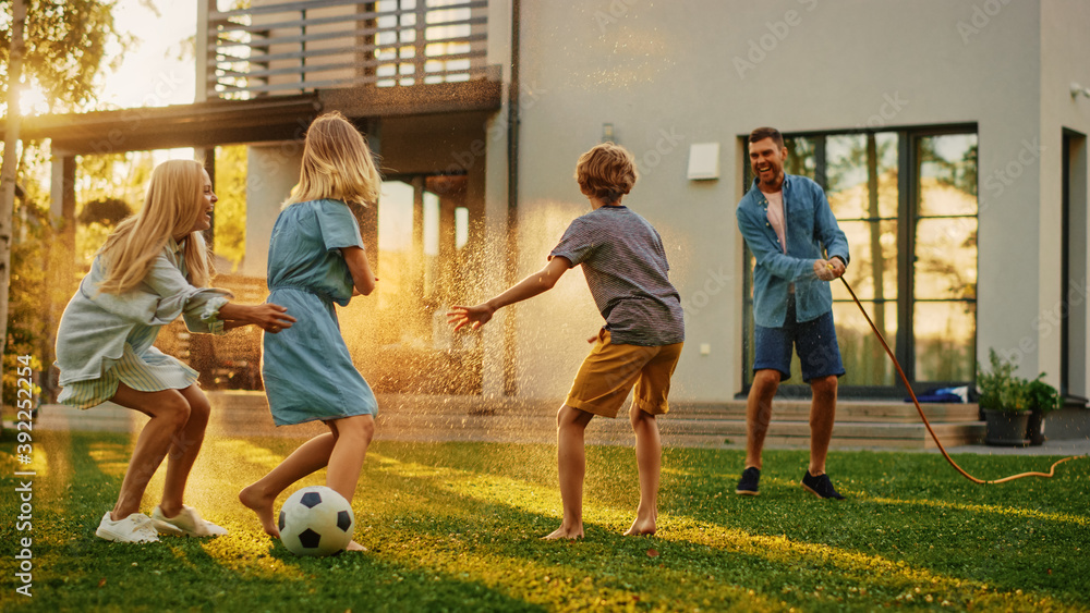 Happy Family of Four Playing with Garden Water Hose, Spraying Each Other. Mother, Father, Daughter a