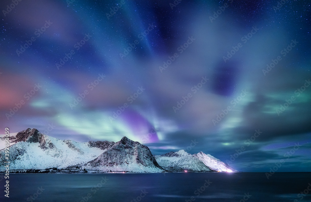 Aurora borealis in Norway. Green northern lights above mountains and ocean. Night winter landscape w