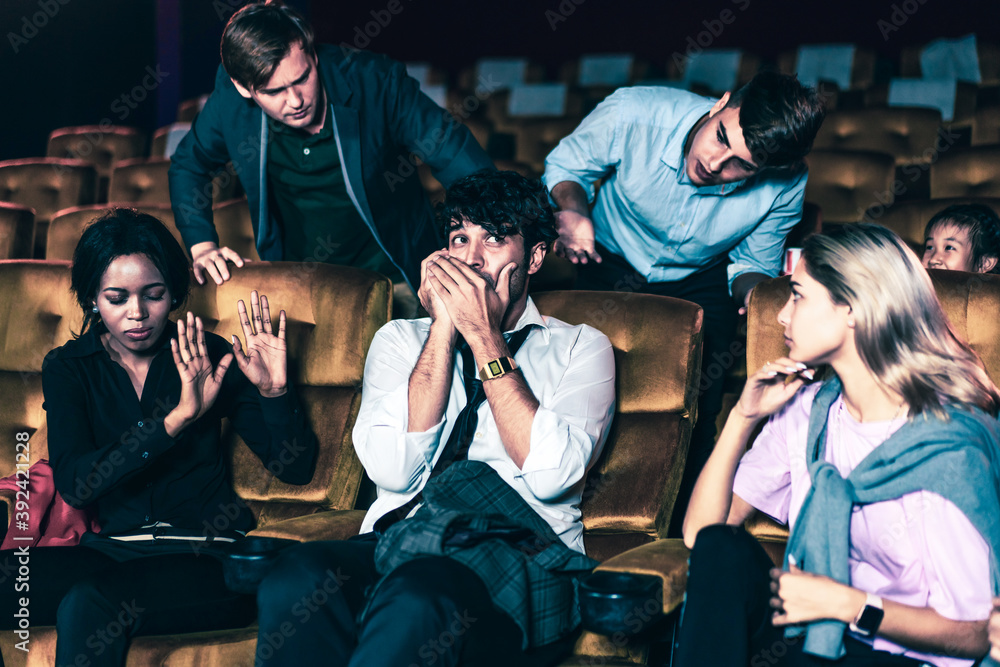 Annoying man talking on the mobile phone at the movie theater people in cinema is angry him