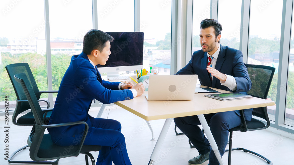 两位商务人士在办公室会议室谈论项目战略。商务人士讨论项目计划