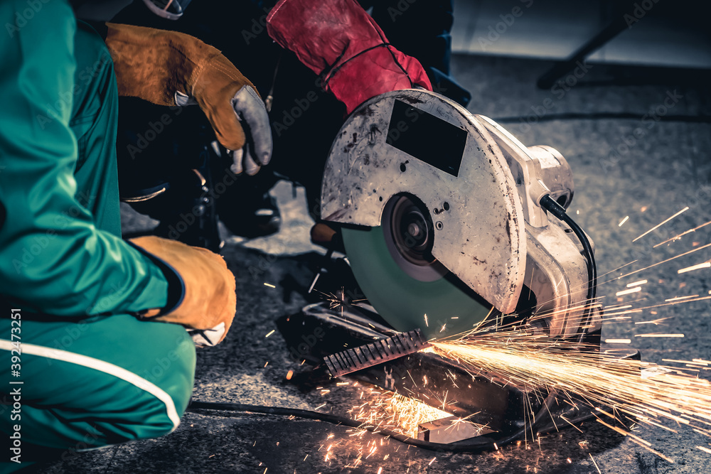 Professional mechanic man is cutting steel metal with rotating carbon blade cutter. Steel industry a