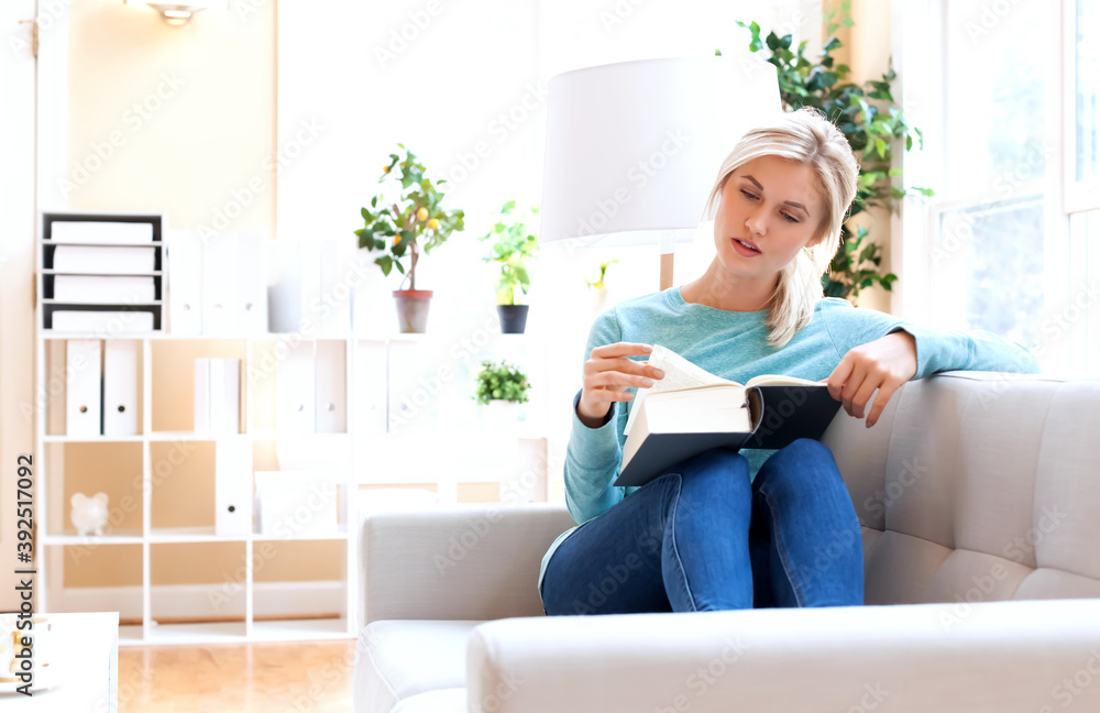 Young woman reading a big book at home