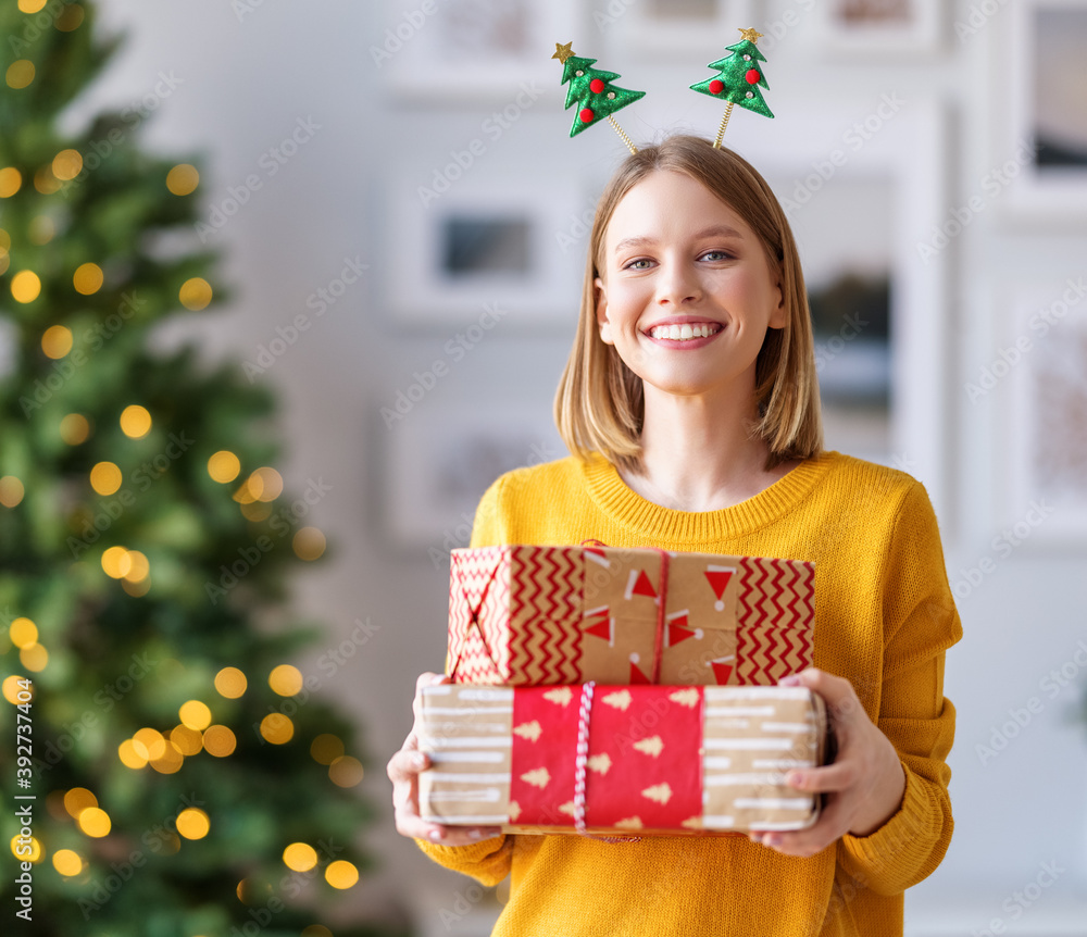 happy   woman   with packed gifts for  Christmas holiday smiles at the camera at home.