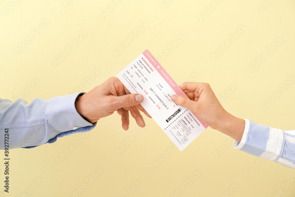 Travel agent giving client ticket on color background