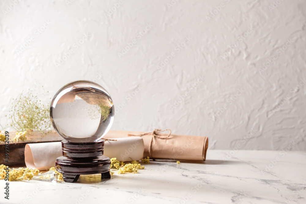 Crystal ball of fortune teller, spell book and scrolls on table