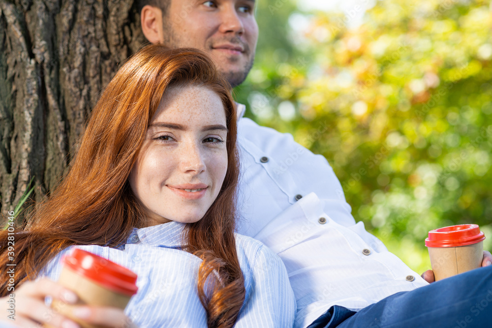 Young couple relaxing with coffee under tree