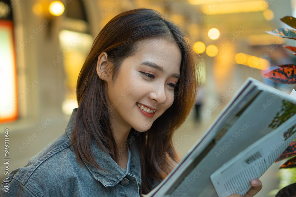 Beautiful Asian girl reading a magazine in the street
